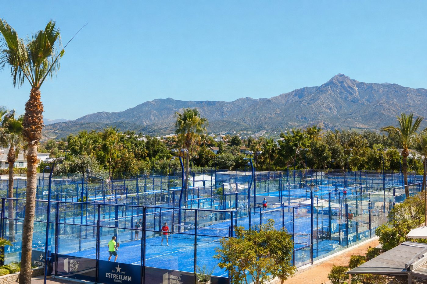 Rows of blue padel courts in Marbella framed by palm trees and the Andalusian mountains